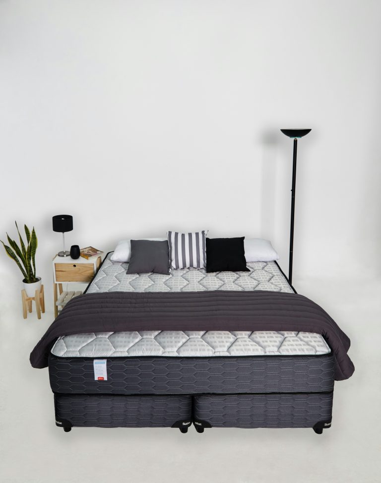 A budget mattress made up on a bed base in a bright bedroom